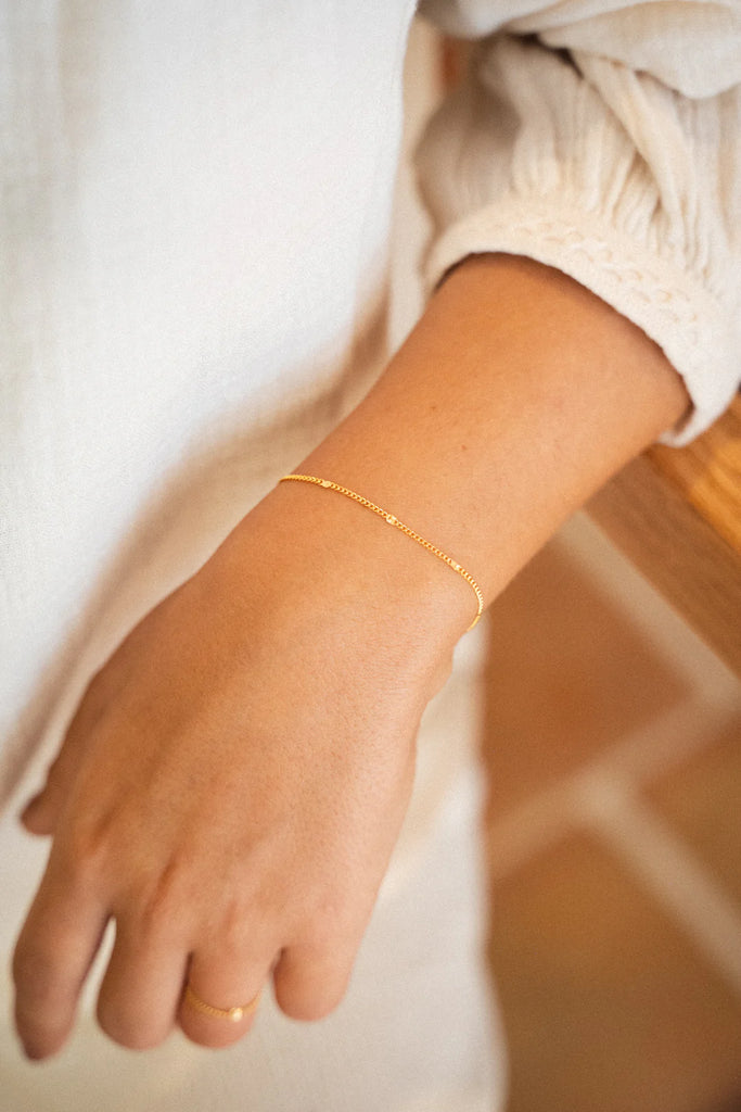 Gold bracelet on a person's wrist with a blurred background