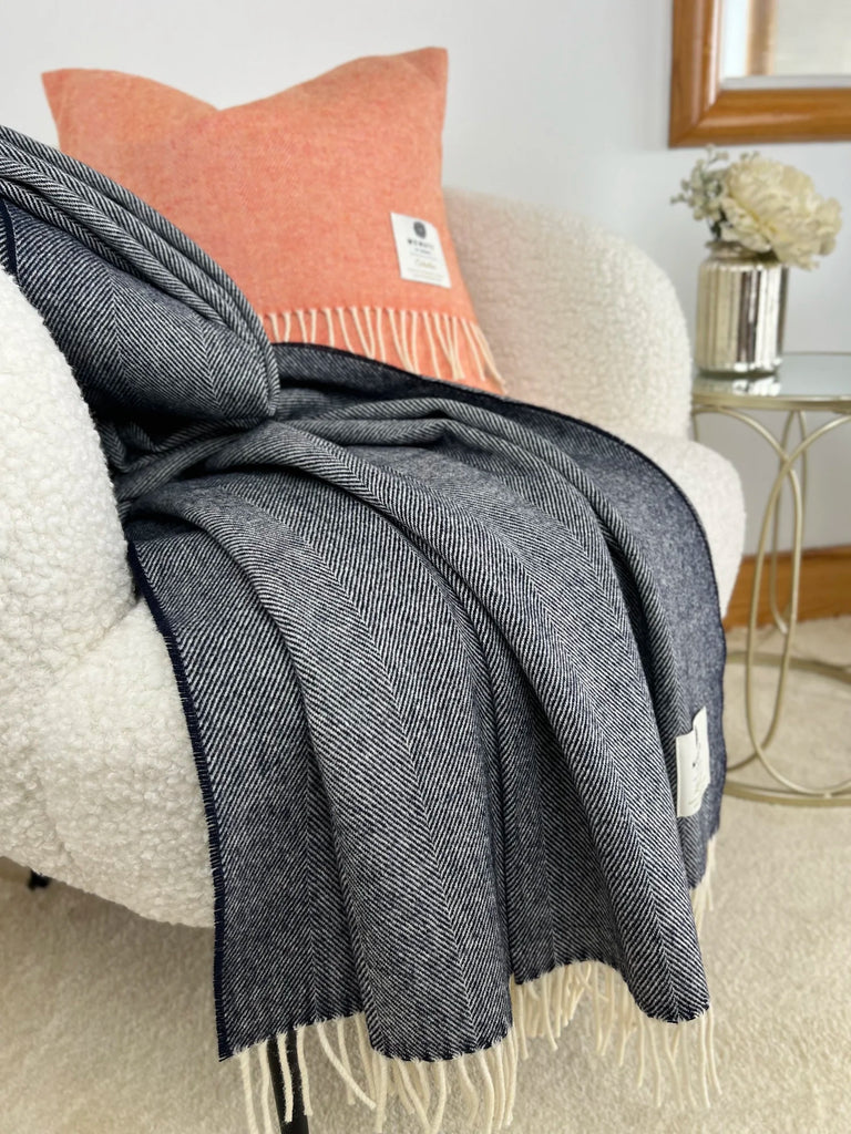 Gray throw blanket draped over a chair with an orange pillow in a cozy living room setting.