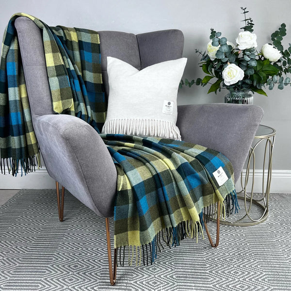 Gray armchair with plaid blanket and white pillow in a room setting.