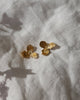 Gold butterfly-shaped earrings on a textured light fabric background