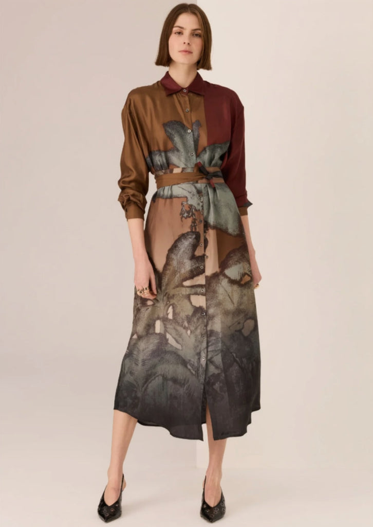 Woman wearing a patterned dress with a belt on a beige background